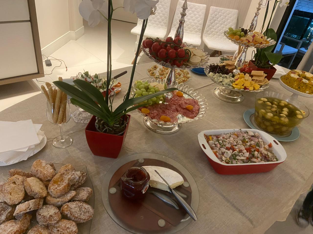 Mesa elegante com tábua de frios, orquídea e salada russa