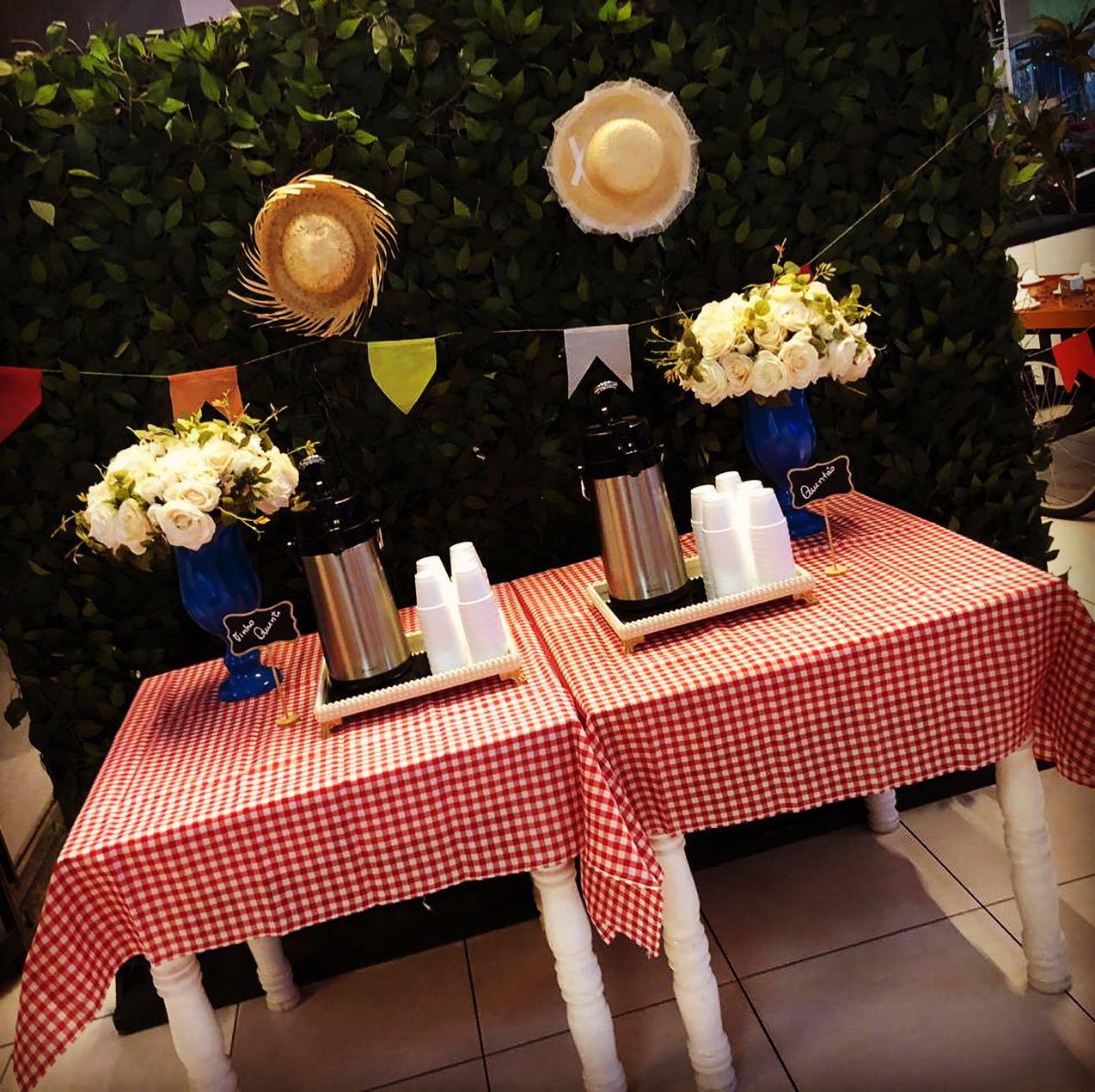 Estação de café com toalha xadrez, chapéus de palha e flores brancas