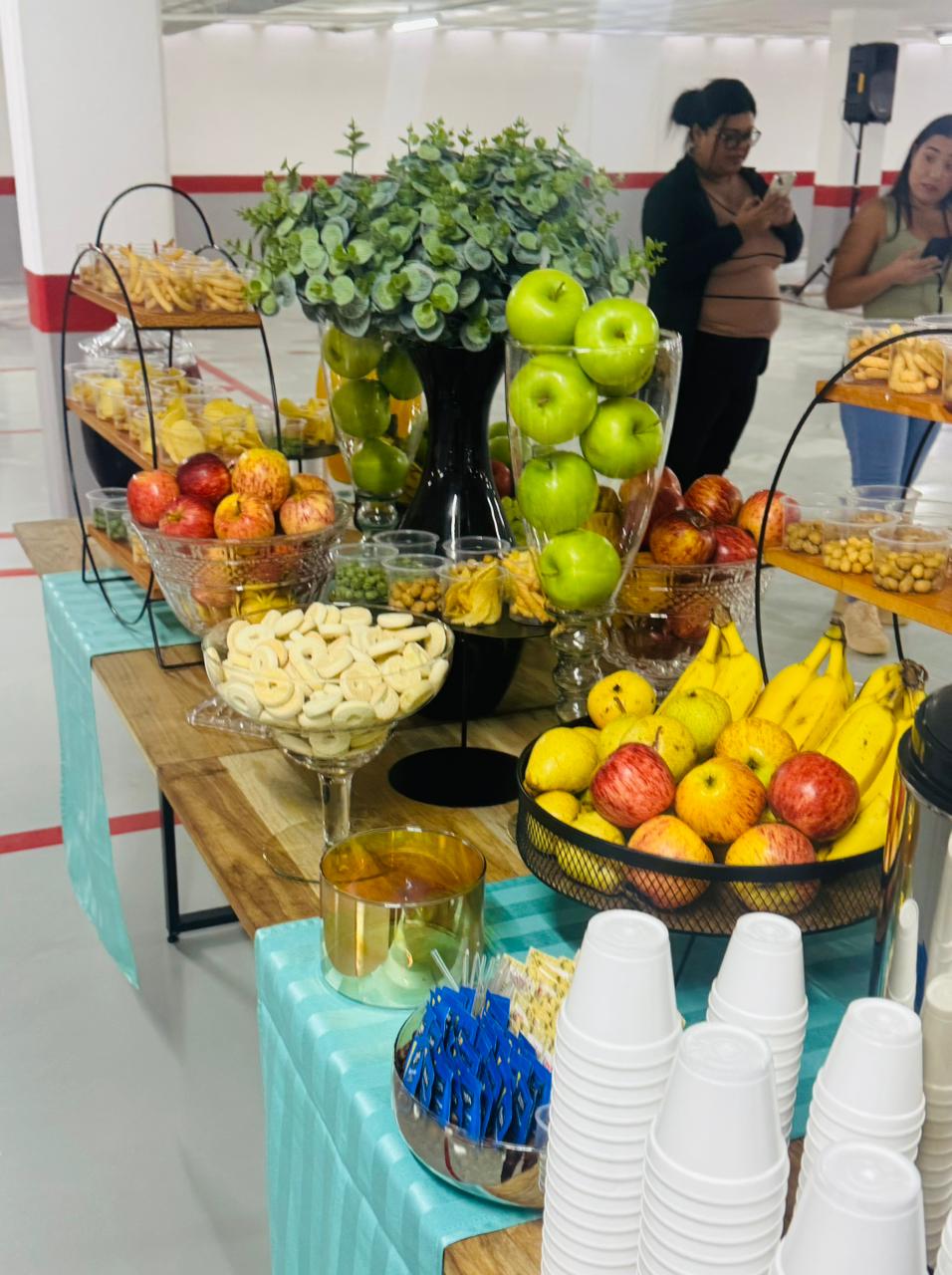 Estação de frutas com maçãs verdes, bananas e arranjo de eucalipto